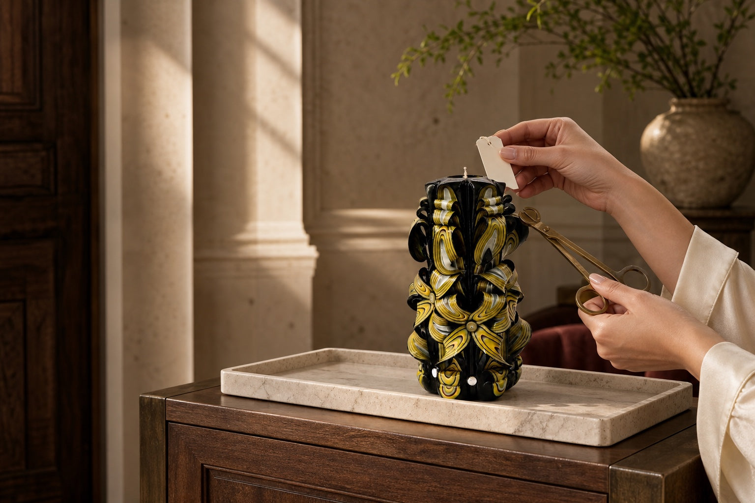 Hands removing the decorative tag from a black and gold Luv Crafts candle before lighting